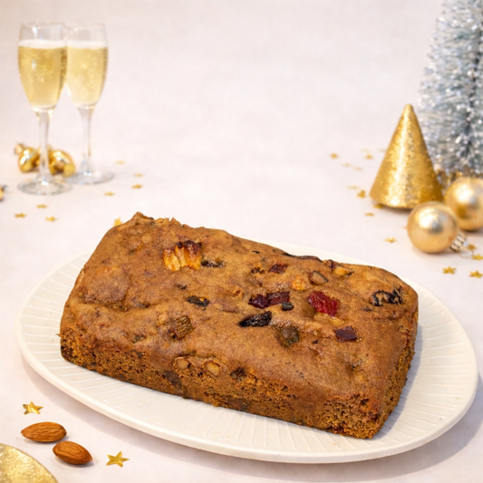 Festive setting with a fruitcake on a plate, flanked by champagne glasses and Christmas decorations.